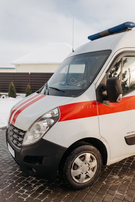 Close-up view of the rear side of a white commercial van parked on a pavement in an urban setting. Three blue plastic rubbish bags, filled and tied, are placed directly behind the vehicle, resting on the ground. The rear door of the van is partially visible, with a subtle vertical handle and red reflector positioned near the left edge. In the background, a storefront or building with large glass windows and a door can be seen, partially obscured by the van. The environment appears clean but functional, suitable for on-site waste collection and private rubbish removal services. The scene highlights an example of independent rubbish disposal, aligned with the type of work carried out by waste clearance companies such as Waste Clearance Notting Hill. The street surface is smooth asphalt, and the overall atmosphere suggests late morning or early afternoon lighting, with natural daylight illuminating the scene evenly, emphasizing the practical nature of rubbish removal and waste management activities in an urban context.